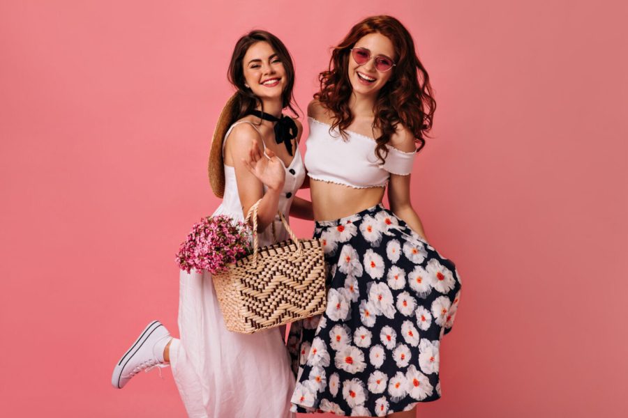 Happy lady in stylish skirt and boater posing on pink background. Young woman in colorful skirt and big hat is very happy on isolated.